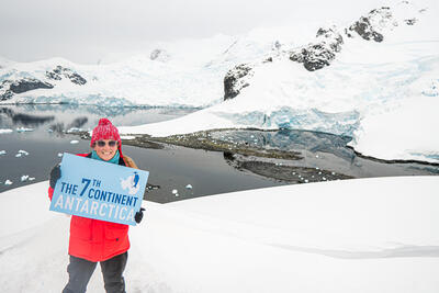 girl standing with a sign in Antarctica