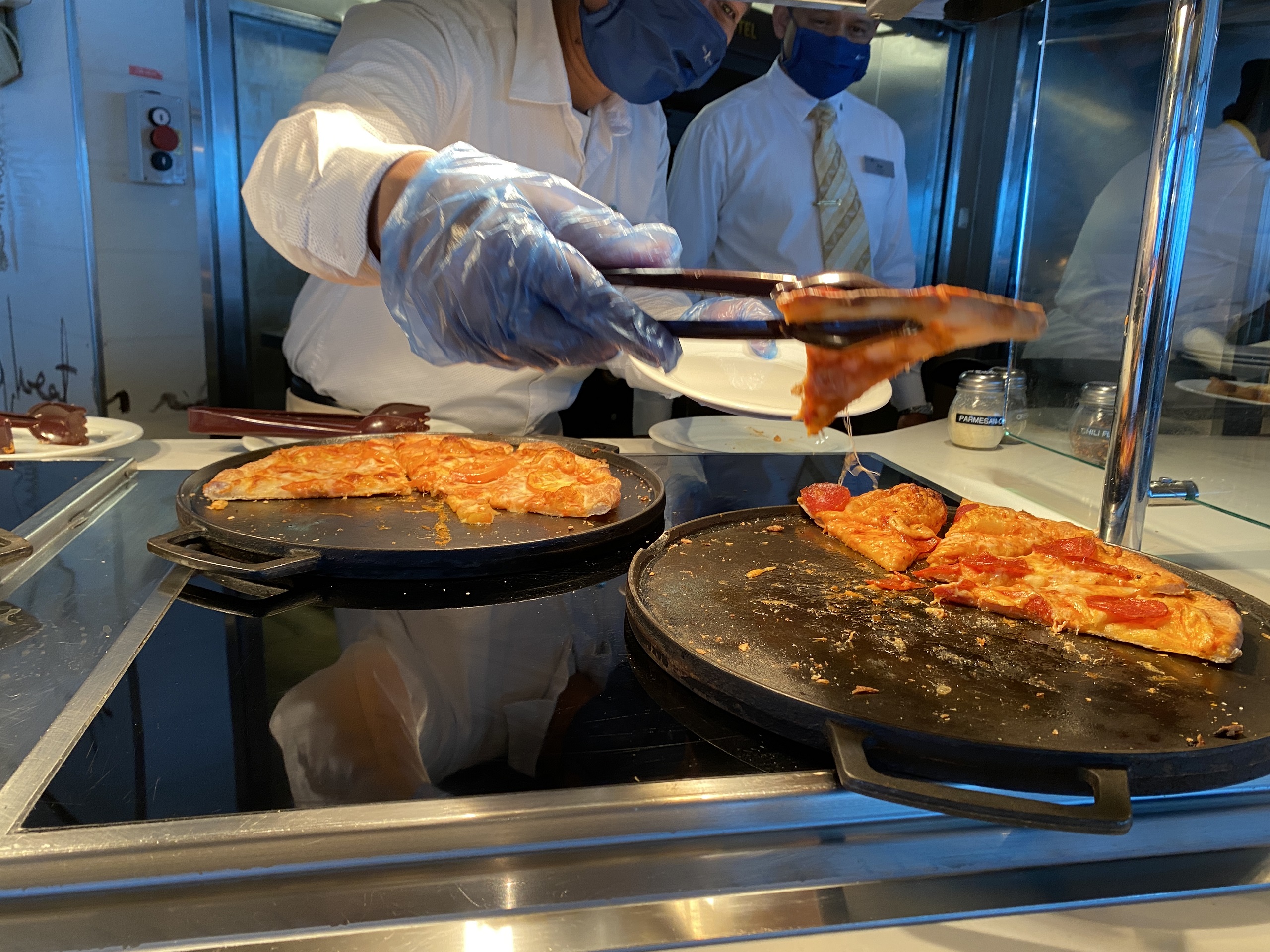 A crewmember holds a slice of pizza that's ready to be served to a passenger on Celebrity Millennium.