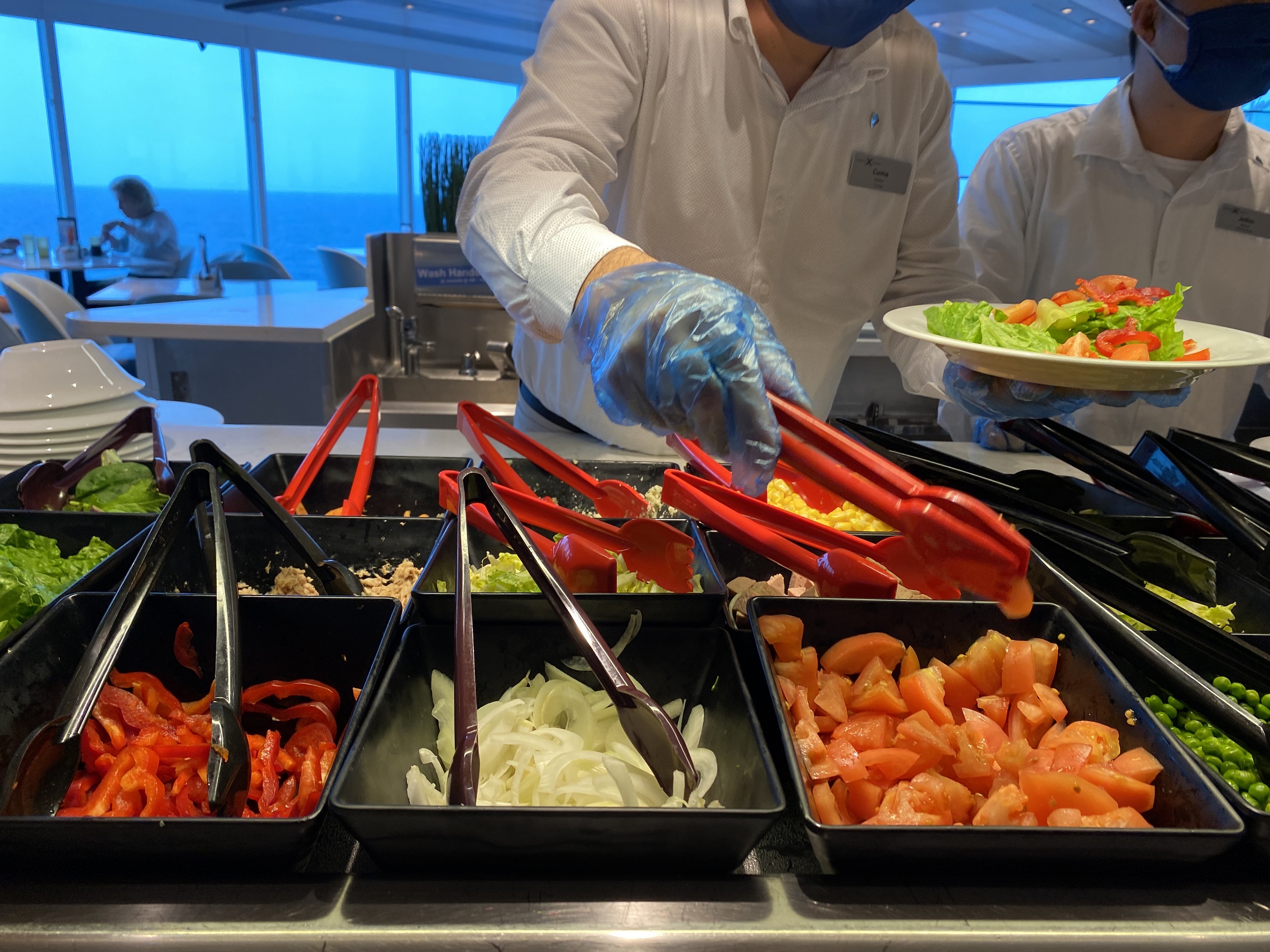 A crewmember serves salad at a buffet station on Celebrity Millennium.