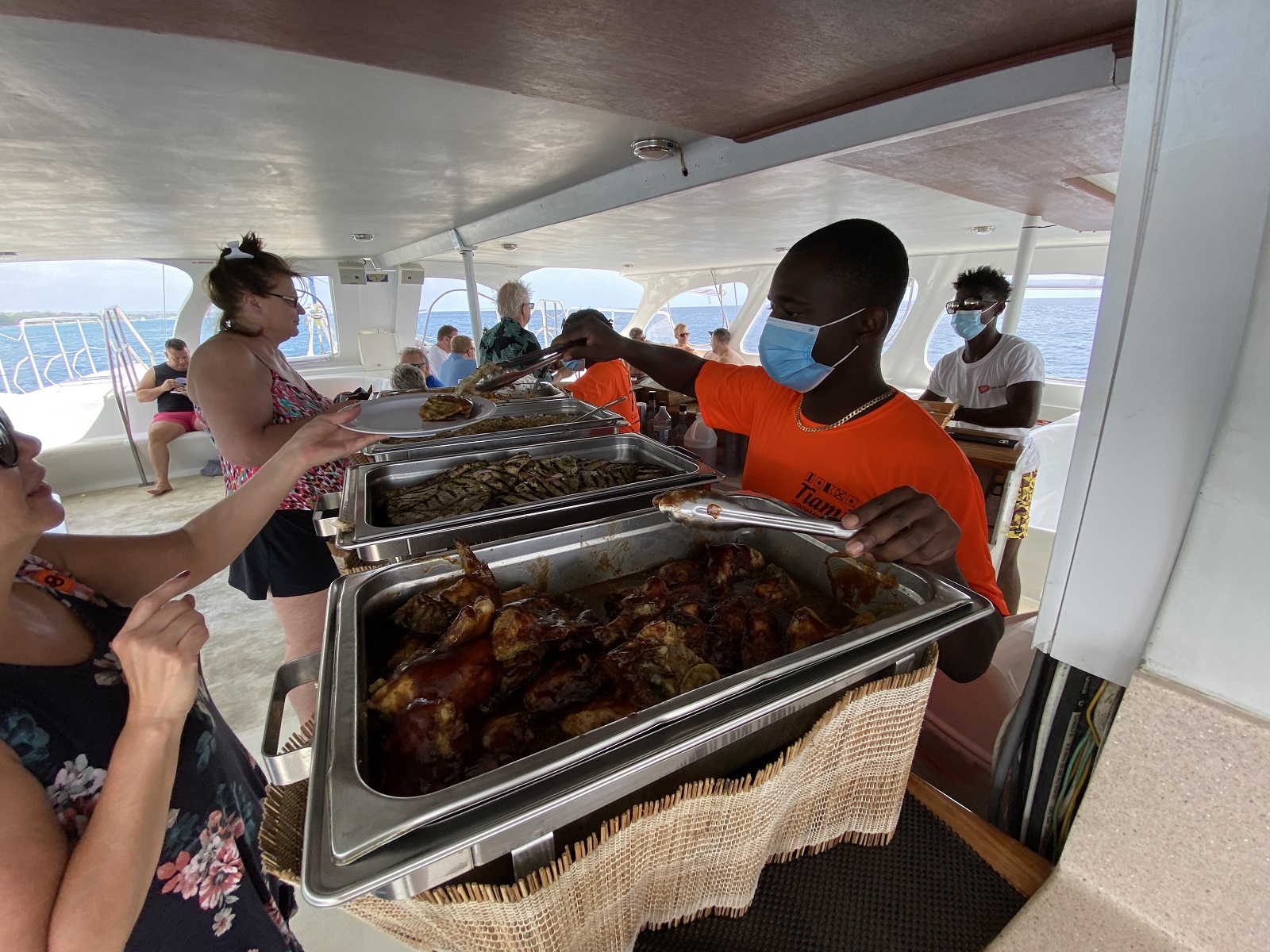 A member of the catamaran's crew serves lunch to cruisers on a shore excursion.