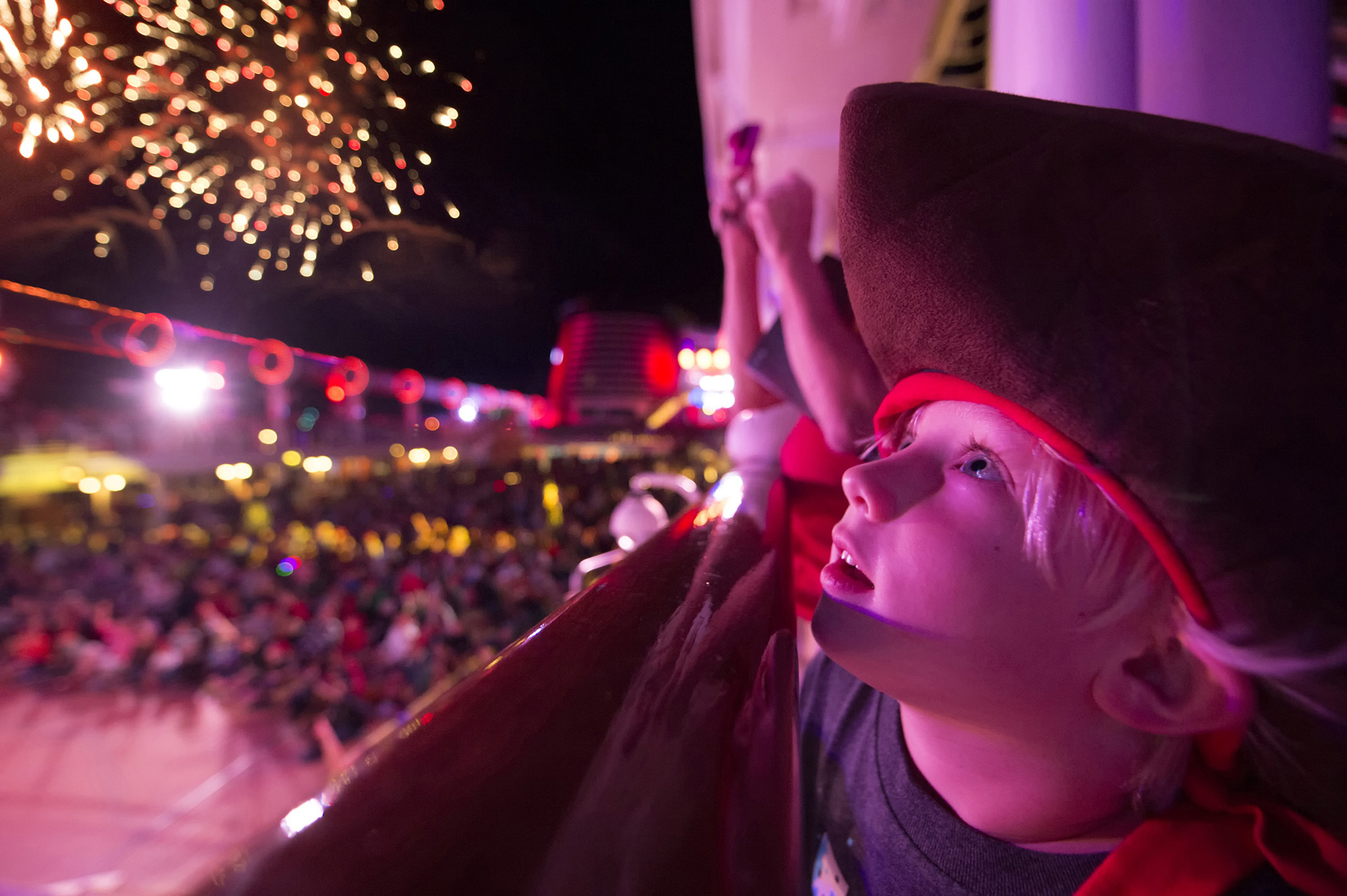 Little boy in pirate costume celebrating Pirate Night on Disney cruise ship with fireworks in the background (source: Disney Cruise Line)