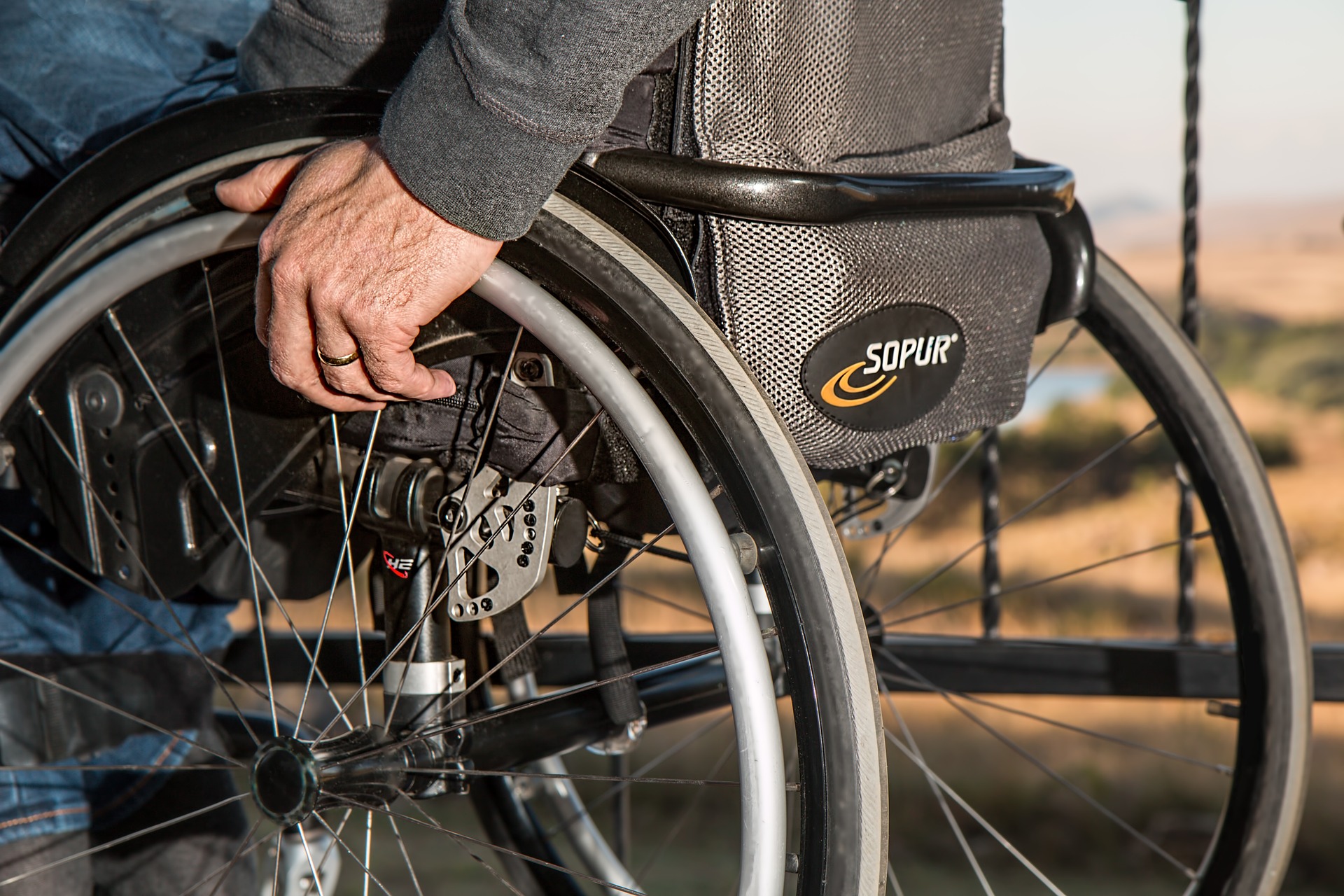 Wheelchair with man's hands on the wheels (source: stevepb, Pixabay)