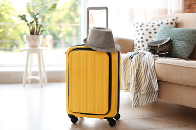 yellow suitcase packed for journey and hat