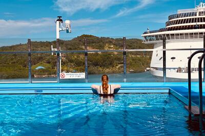 young woman looks out at the distance while in a pool on Carnival Celebration