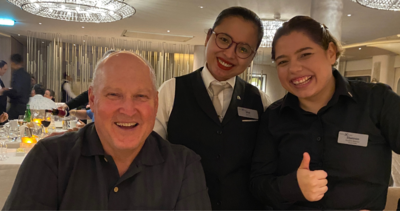 Two employees pose with Brian in the main dining room