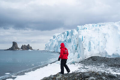 man standing in front of a glacier