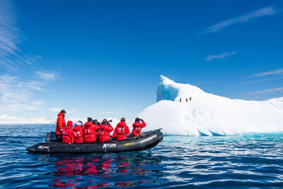 Zodiac boat cruising around an iceberg