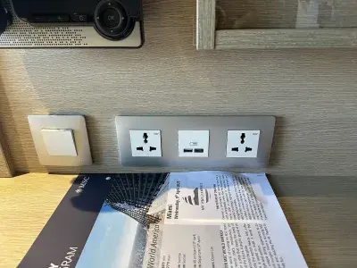 A variety of electrical outlets near the desk in a cruise ship cabin