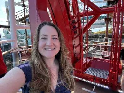 A woman standing in front of the seating area on one of the swings for Cliffhanger, a ride attraction on MSC World America