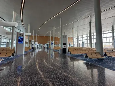 A cruise terminal walkway with rows of wooden chairs and floor-to-ceiling windows