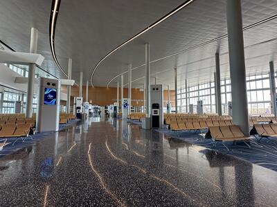 A cruise terminal walkway with rows of wooden chairs and floor-to-ceiling windows