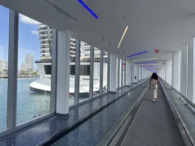 A woman walking down a long corridor to reach the gangway to her cruise ship