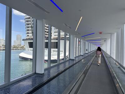 A woman walking down a long corridor to reach the gangway to her cruise ship