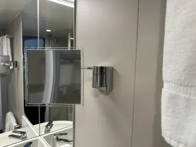 A wall-mounted makeup mirror in a cruise ship bathroom