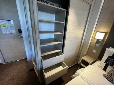 One side of a cruise ship cabin closet, showing shelves and drawers