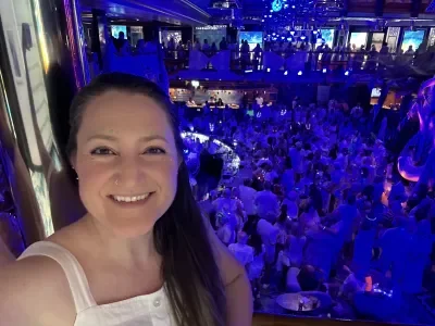 Selfie of a woman with a glow party behind her in a cruise ship atrium