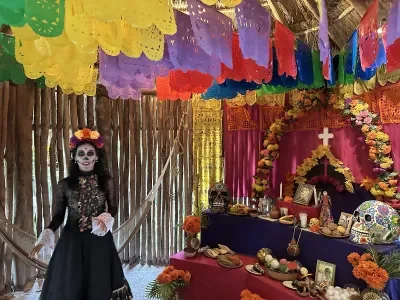 A woman dressed as La Catrina next to an altar as part of a cruise ship shore excursion about Dia De Los Muertos in Cozumel, Mexico