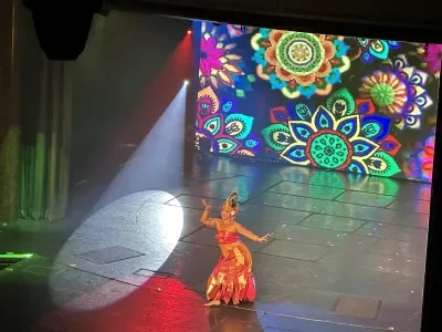A cruise ship crew member performs a traditional Indonesian dance on stage during a crew talent show