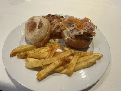A white plate with a salmon slider and French fries