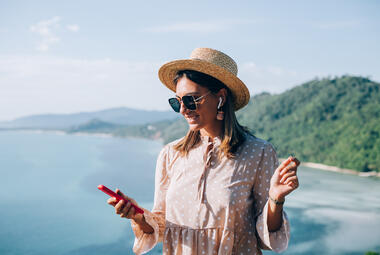 woman listens to music on her AirPods while on vacation