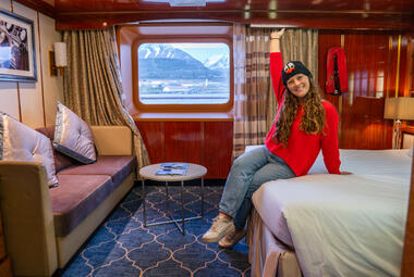 girl sitting on bed in cruise ship cabin